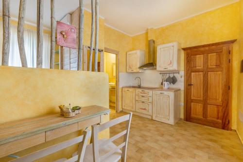 a kitchen with yellow walls and a wooden table at Palazzo Beddoro in San Pantaleo