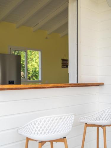 two white chairs sitting in front of a mirror at Villa Aura in Grand-Bourg