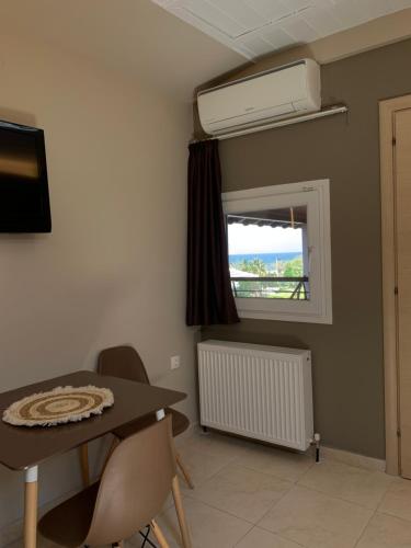 a room with a table and chairs and a window at Rodolithos Beach in Stavros