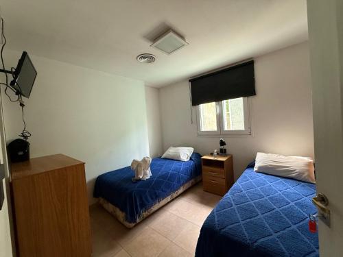 1 dormitorio con 2 camas y un osito de peluche en la cama en La Posta de Adolfo, en Las Heras