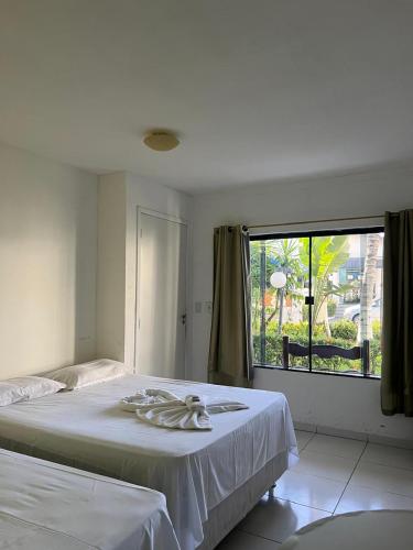 a bedroom with a bed and a large window at Oasis Praia Hotel in Coroa Vermelha