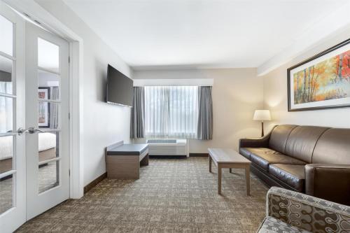 a hotel room with a couch and a window at Best Western Plus Windjammer Inn & Conference Center in Burlington