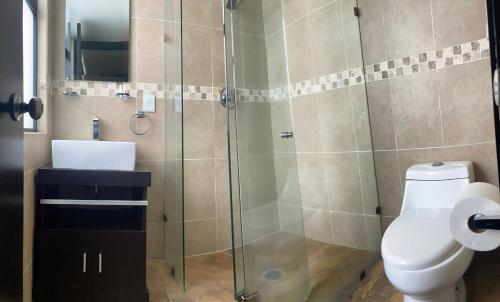 ein Badezimmer mit Toilette und Glasdusche in der Unterkunft Casa Lomas de Cuernavaca in Jiutepec