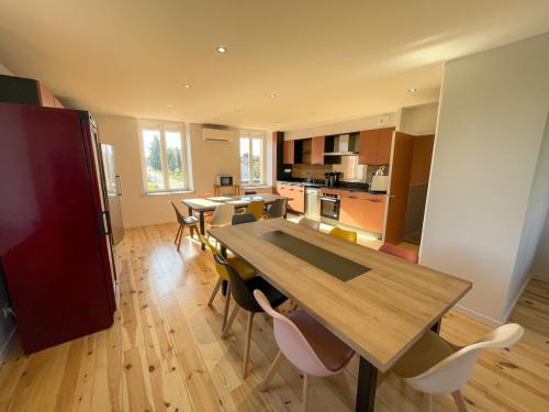 une cuisine et une salle à manger avec une table et des chaises en bois dans l'établissement La Bamboche - Gîte et salle, à Lapte