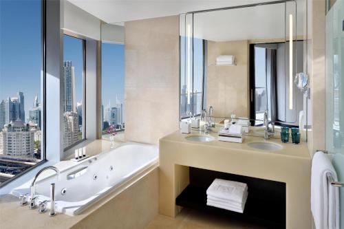 a bathroom with a tub and two sinks and a window at Kempinski Central Avenue Dubai in Dubai
