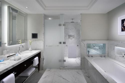 a white bathroom with a tub and a shower at Kempinski The Boulevard Dubai in Dubai