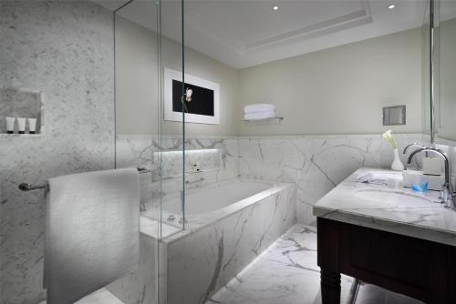 a white bathroom with a tub and a sink at Kempinski The Boulevard Dubai in Dubai