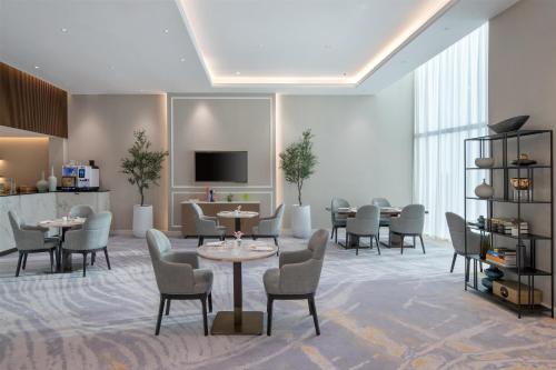 a waiting room with tables and chairs and a tv at Kempinski Central Avenue Dubai in Dubai
