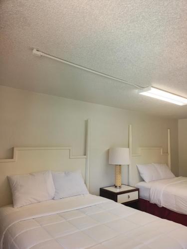 a room with two beds and a lamp on a table at Super Inn Motel in Oklahoma City