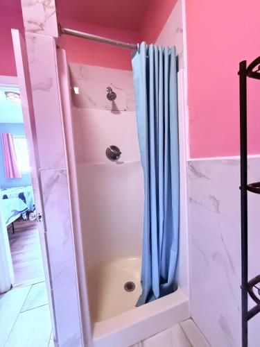 a shower with a blue shower curtain in a bathroom at Twilight Motel in Wildwood