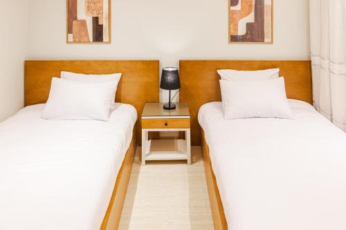 two beds in a room with a side table at Elegance Tower in Cairo
