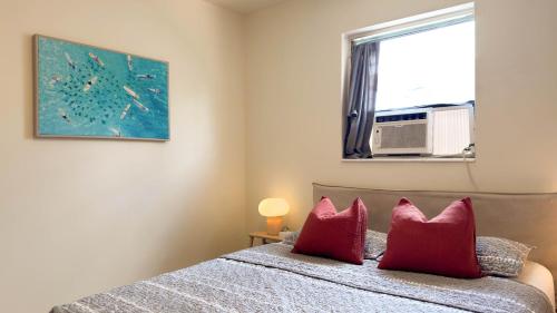 una camera da letto con un letto con cuscini rossi e una finestra di Cozy Garden Bungalow - Pets/Parking/Beach a Fort Lauderdale