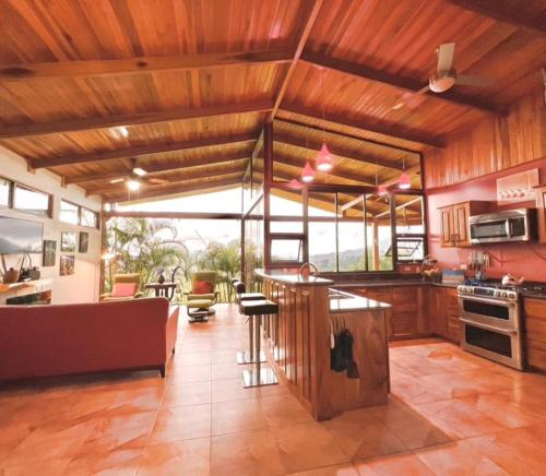 a kitchen with wooden ceilings and a living room at Romantic Retreat Volcano View! River Trail! in El Castillo de la Fortuna