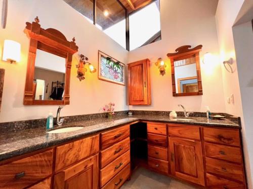 a bathroom with two sinks and a large mirror at Romantic Retreat Volcano View! River Trail! in El Castillo de la Fortuna