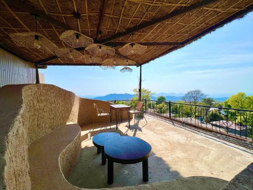 a patio with a bench and a blue stool at IRAH by Parvatah in Bīr