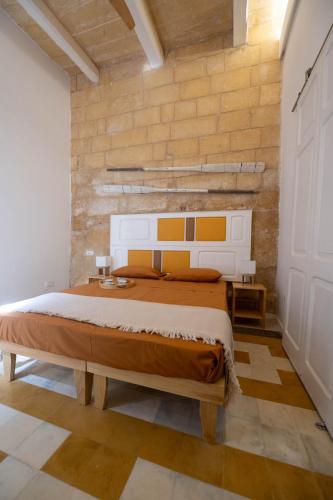 una camera da letto con un letto grande e un muro di mattoni di Blue House 9 Rooms & Breakfast a Birgu (Vittoriosa)