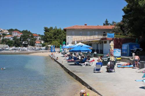 un gruppo di persone seduti su una spiaggia vicino all'acqua di Apartments with parking space Palit, Rab - 4983 a Rab