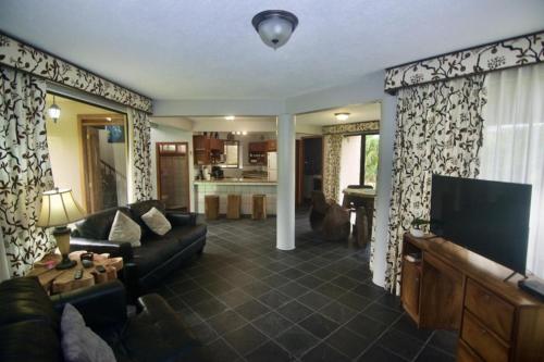 a living room with a couch and a tv at Firefly Hilltop Retreat, Swimming Pool Volcano! in El Castillo de La Fortuna