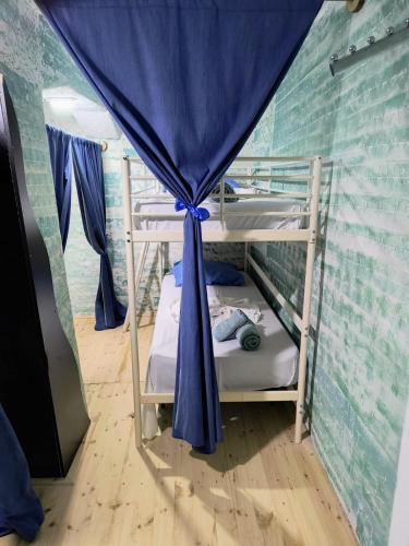 a room with two bunk beds with a blue curtain at War Bunker Hostel in Sarandë