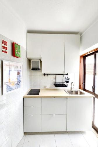 a kitchen with white cabinets and a sink at Casa de KanYan in Foz do Arelho
