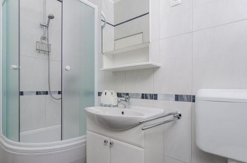 a white bathroom with a sink and a shower at Apartments by the sea Orebic, Peljesac - 24372 in Orebić