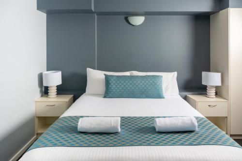 a bedroom with a large bed with two night stands at Nesuto The Entrance in The Entrance