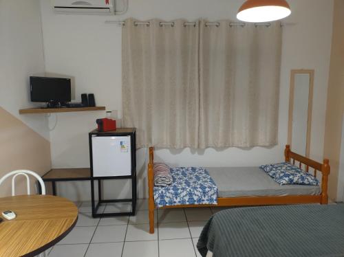 a bedroom with a bed and a table and a window at Pousada Flay 7 minutos Próximo do Aeroporto de Florianópolis in Florianópolis