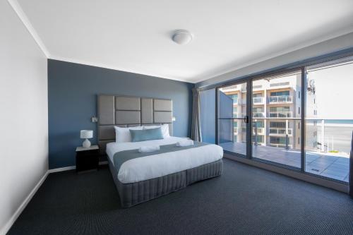 a bedroom with a large bed and a large window at Nesuto The Entrance in The Entrance