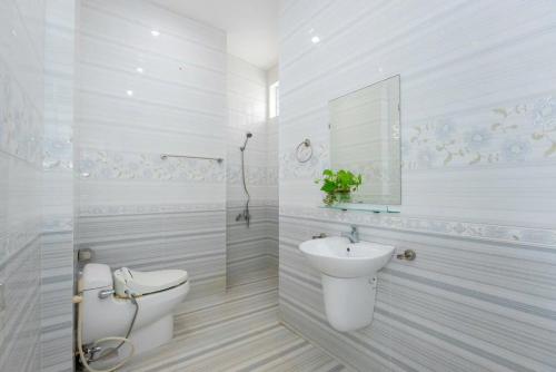 a white bathroom with a toilet and a sink at Hoàng My Villa - 82 Hoàng Hoa Thám in Vung Tau