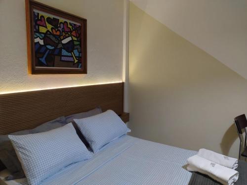 a bedroom with a bed with a painting on the wall at Pousada Flay 7 minutos Próximo do Aeroporto de Florianópolis in Florianópolis
