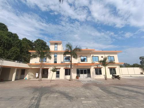 un grand bâtiment avec des palmiers devant dans l'établissement Hotel O Home Kanak Hotel & Resort Homestay, à Ayodhya