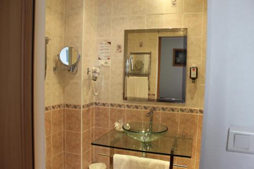 a bathroom with a glass sink and a mirror at Hotel Bristol in Châlons-en-Champagne