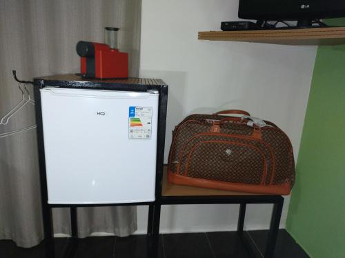 a suitcase sitting on a table next to a refrigerator at Pousada Flay 7 minutos Próximo do Aeroporto de Florianópolis in Florianópolis