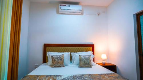 a bedroom with a bed with pillows and a lamp at Serene Villa Airport Transit in Katunayake