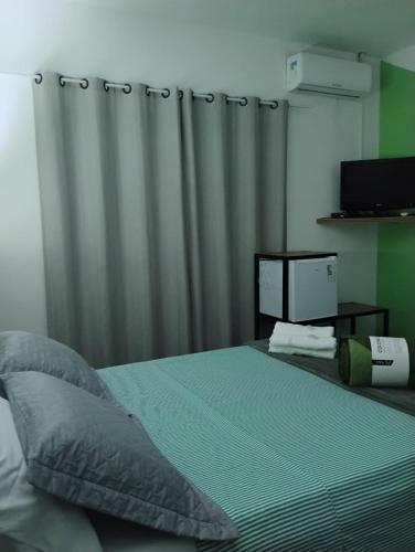a bedroom with a bed with a curtain and a television at Pousada Flay 7 minutos Próximo do Aeroporto de Florianópolis in Florianópolis