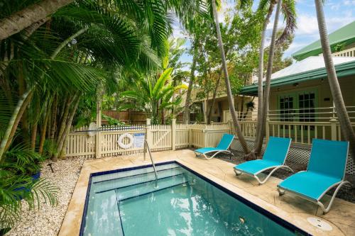 a swimming pool with two blue chairs and a house at Heron Hideaway in Key West