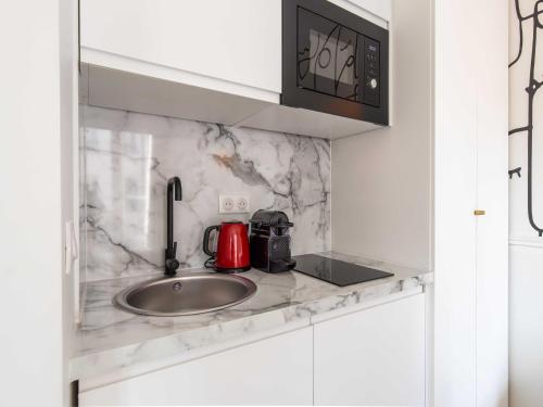 un comptoir de cuisine avec un évier et un micro-ondes dans l'établissement Magnificent studio - 2P - Pigalle Moulin Rouge, à Paris