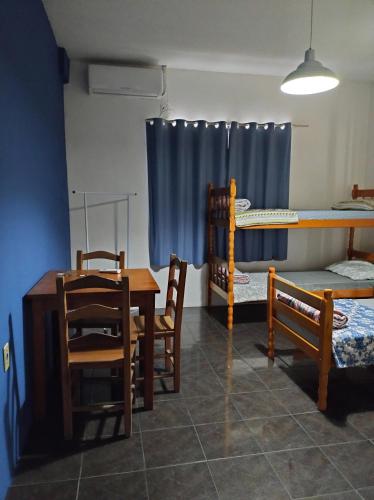 a room with a table and chairs and bunk beds at Pousada Flay 7 minutos Próximo do Aeroporto de Florianópolis in Florianópolis
