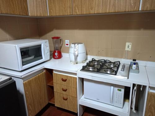 a kitchen with a stove and a microwave at Casa inteira no Centro de Jacareí próximo à São José dos Campos in Jacareí