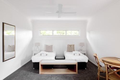 a white room with two beds and a table at The Wellness Farm Broke in Broke