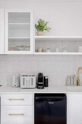 a kitchen with white cabinets and a black dishwasher at The Wellness Farm Broke in Broke