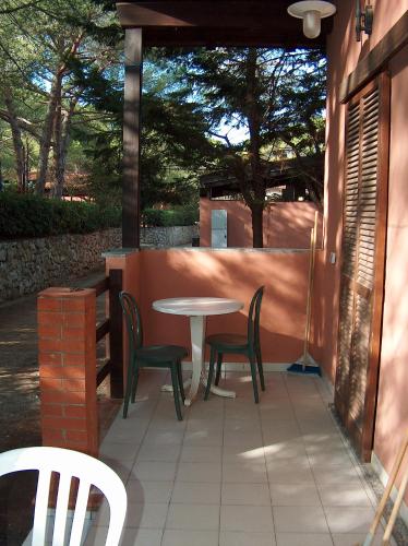 a patio with a table and chairs and a fence at Camping Lacona Pineta in Capoliveri