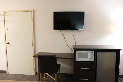 a room with a desk with a microwave and a tv on the wall at Sterling Inn near IAG Airport in Niagara Falls