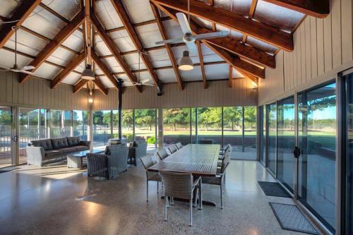 a dining room with a table and chairs and windows at Nepeta Cataria Estate - Echuca Holiday Homes in Moama