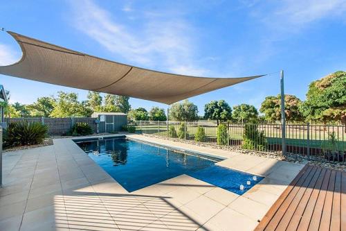 a swimming pool with a large umbrella over it at Nepeta Cataria Estate - Echuca Holiday Homes in Moama