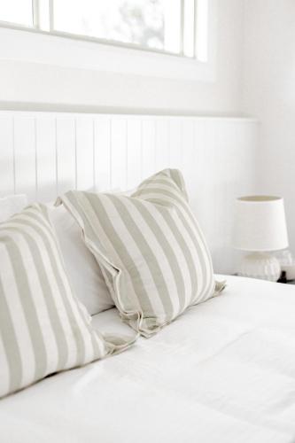 a white bed with two pillows on top of it at The Wellness Farm Broke in Broke