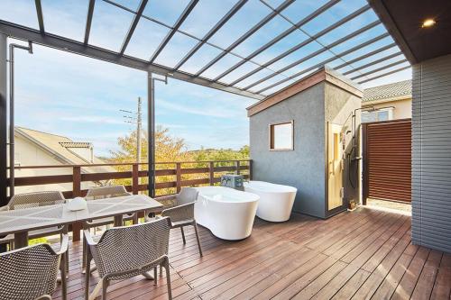 a balcony with tables and chairs and a large window at Maigre atelier in Ito