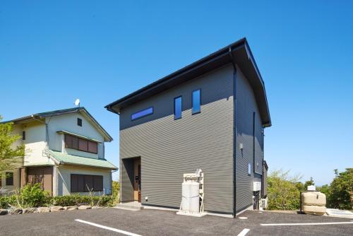 a building with blue windows and a parking lot at Maigre atelier in Ito
