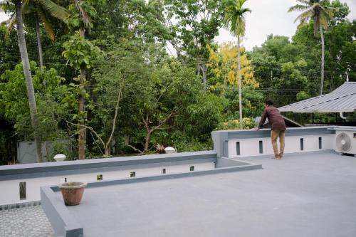 a man standing on the ledge of a roof at Varkala- Aroma Ac pvt Villa hammocks kitchen in Varkala