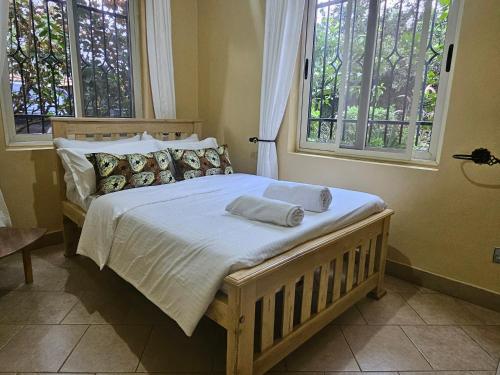 a bed in a bedroom with two windows at Cosy, private and modern in Kampala